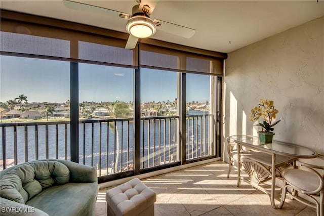 sunroom / solarium with ceiling fan and a water view