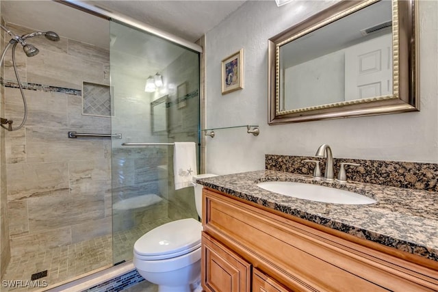 bathroom featuring toilet, a shower with shower door, and vanity