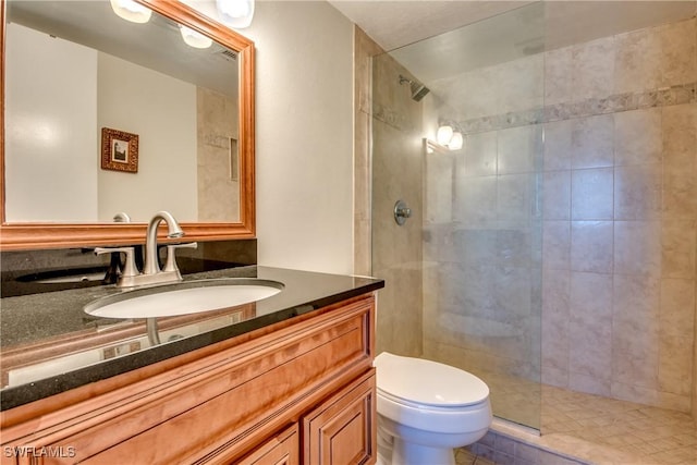 bathroom with toilet, vanity, and a shower with door