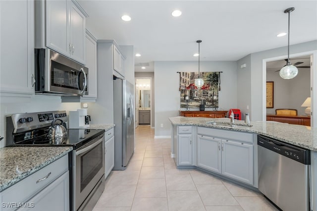 kitchen featuring light stone counters, stainless steel appliances, hanging light fixtures, and sink