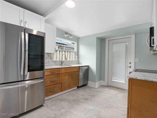 kitchen featuring lofted ceiling, decorative backsplash, sink, appliances with stainless steel finishes, and light stone counters