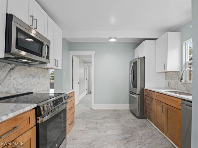 kitchen with white cabinetry, stainless steel appliances, tasteful backsplash, light stone countertops, and sink