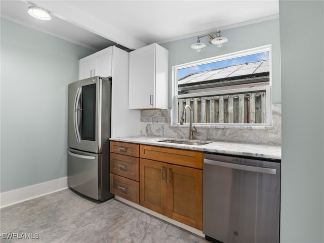 kitchen with decorative backsplash, light stone counters, appliances with stainless steel finishes, white cabinetry, and a sink