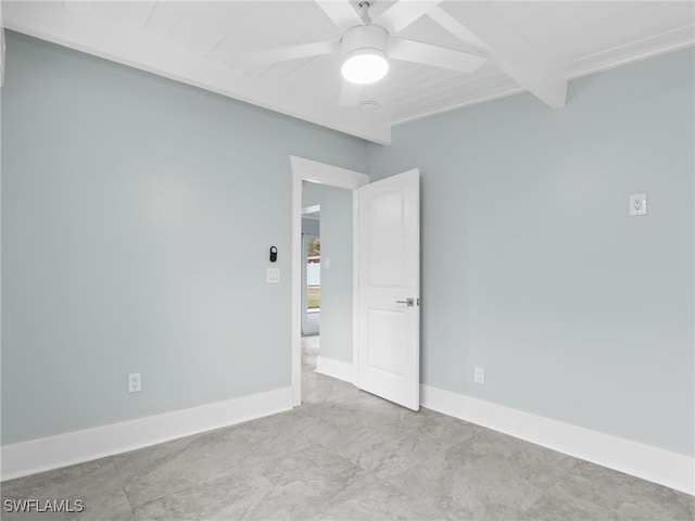 spare room with marble finish floor, ceiling fan, baseboards, and beam ceiling