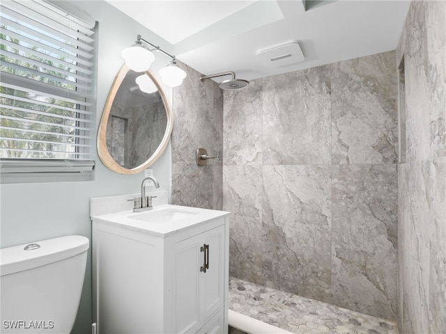 bathroom featuring a tile shower, vanity, and toilet