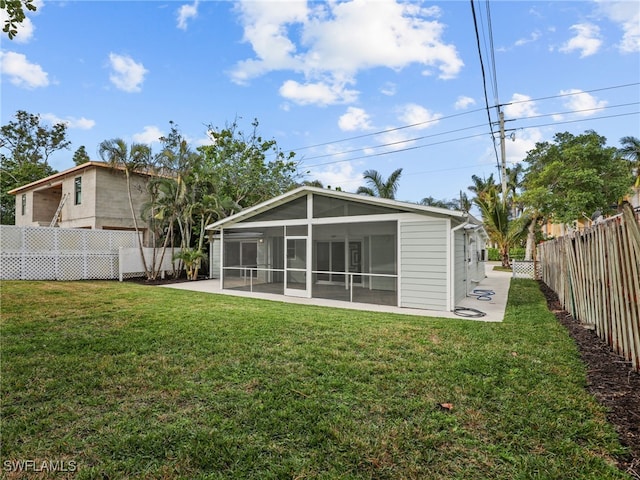 rear view of property with a yard, a fenced backyard, and a sunroom