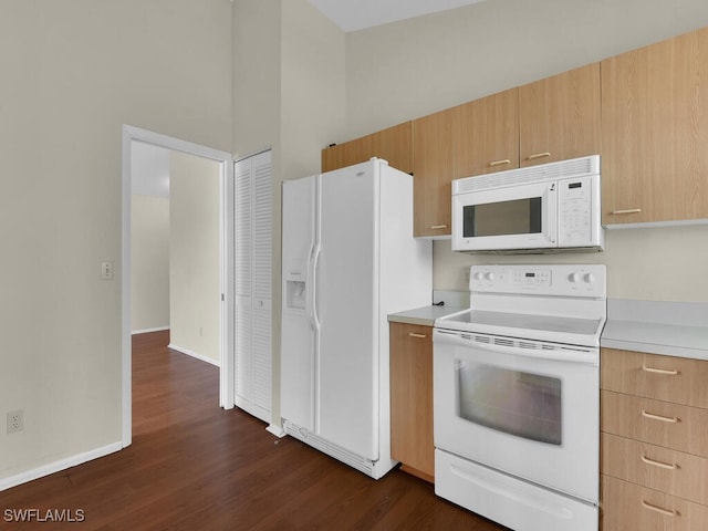 kitchen featuring dark hardwood / wood-style flooring, white appliances, light brown cabinets, and a high ceiling