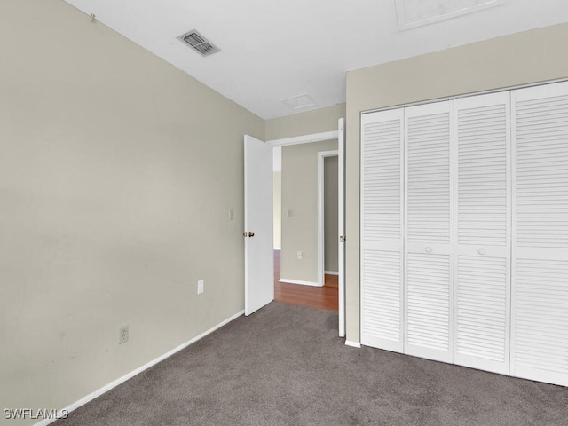 unfurnished bedroom with dark carpet and a closet