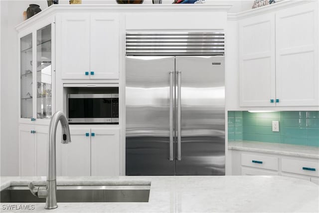 kitchen featuring stainless steel appliances, decorative backsplash, white cabinetry, and sink