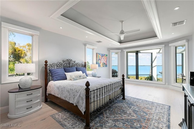 bedroom featuring ceiling fan, light hardwood / wood-style flooring, and a tray ceiling