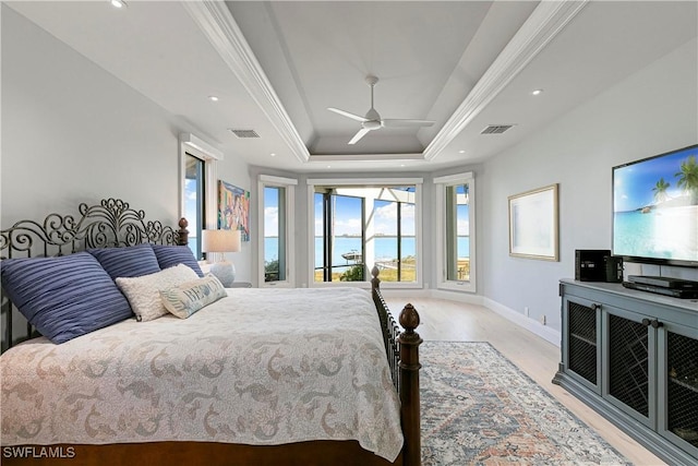 bedroom featuring ceiling fan, light hardwood / wood-style floors, crown molding, and a tray ceiling