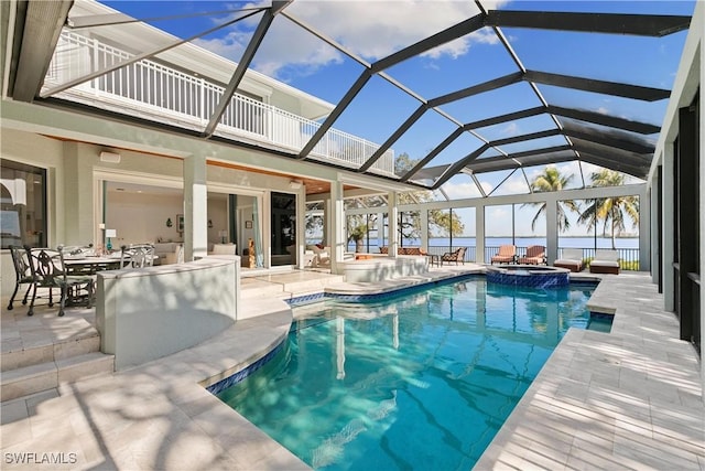 view of pool featuring a lanai, a patio area, an in ground hot tub, and a water view