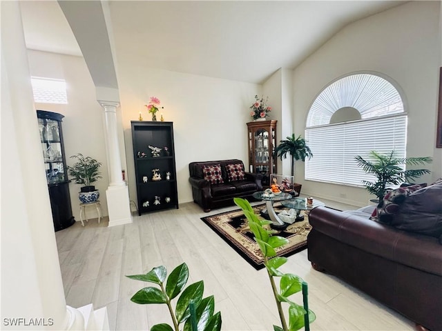 living room featuring decorative columns, vaulted ceiling, and light hardwood / wood-style flooring