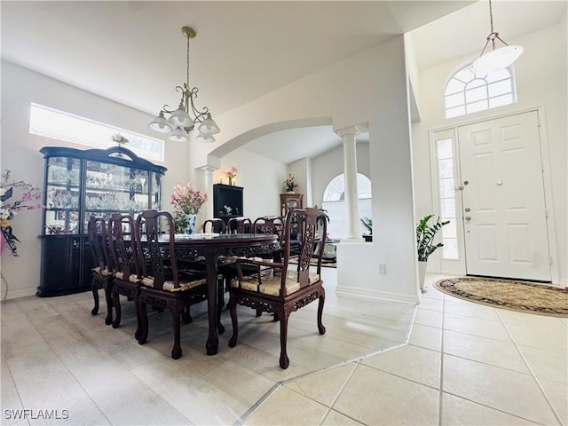 tiled dining space featuring ornate columns and a chandelier