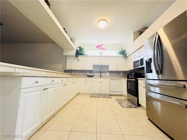 kitchen with light tile patterned floors, decorative backsplash, white cabinets, appliances with stainless steel finishes, and sink