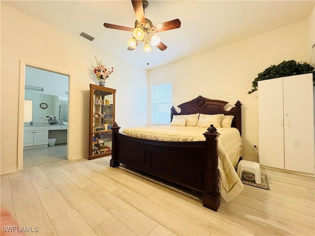 bedroom with ceiling fan, light wood-type flooring, and ensuite bath