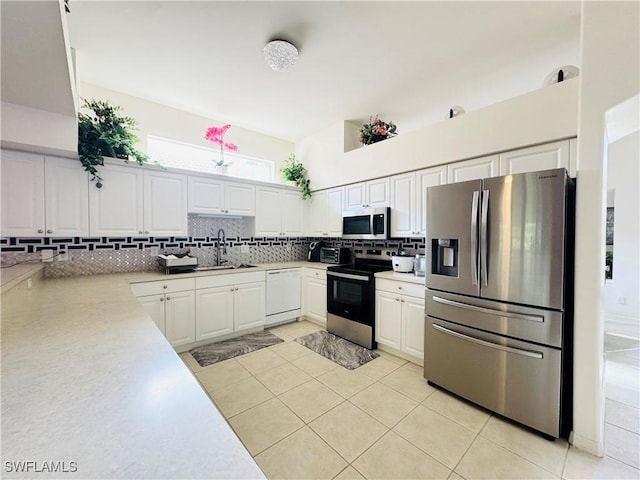 kitchen featuring sink, appliances with stainless steel finishes, light tile patterned floors, and white cabinetry