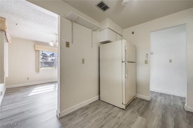 kitchen featuring white refrigerator, a textured ceiling, a chandelier, and light hardwood / wood-style flooring