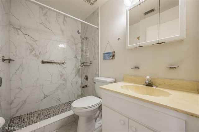 bathroom with a tile shower, vanity, and toilet