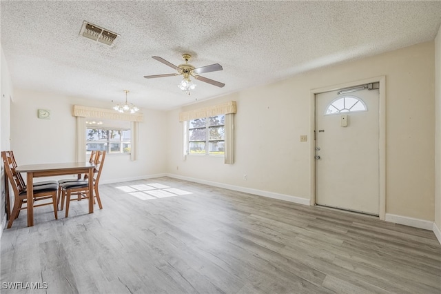 entryway with a healthy amount of sunlight, hardwood / wood-style floors, and ceiling fan with notable chandelier