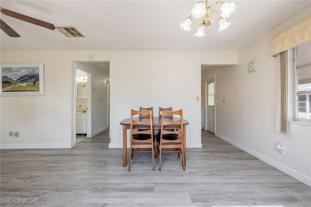 dining room featuring ceiling fan with notable chandelier, a textured ceiling, a healthy amount of sunlight, and light hardwood / wood-style flooring