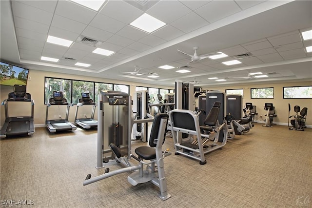 gym featuring a healthy amount of sunlight, a drop ceiling, and ceiling fan