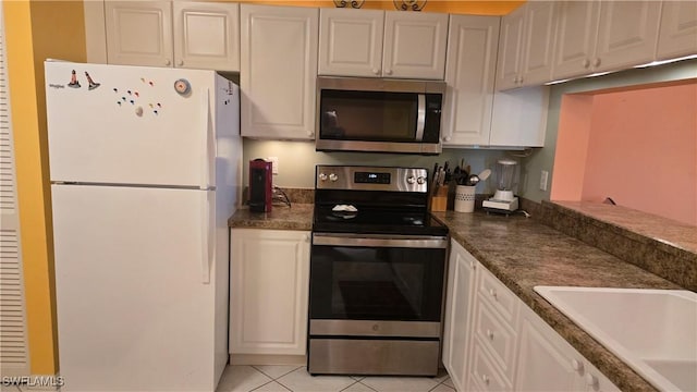 kitchen featuring white cabinets, stainless steel appliances, sink, and light tile patterned flooring