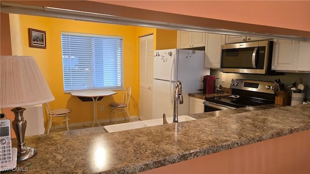 kitchen featuring sink, stainless steel appliances, white cabinetry, and kitchen peninsula