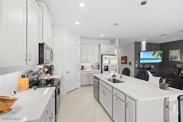 kitchen featuring pendant lighting, sink, white cabinetry, an island with sink, and stainless steel appliances