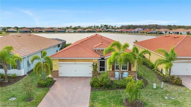 mediterranean / spanish-style home featuring a front lawn, a garage, and a water view