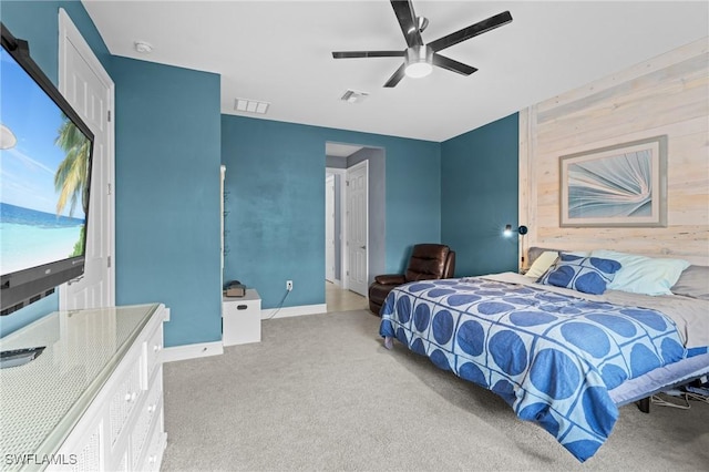 carpeted bedroom featuring ceiling fan and wooden walls