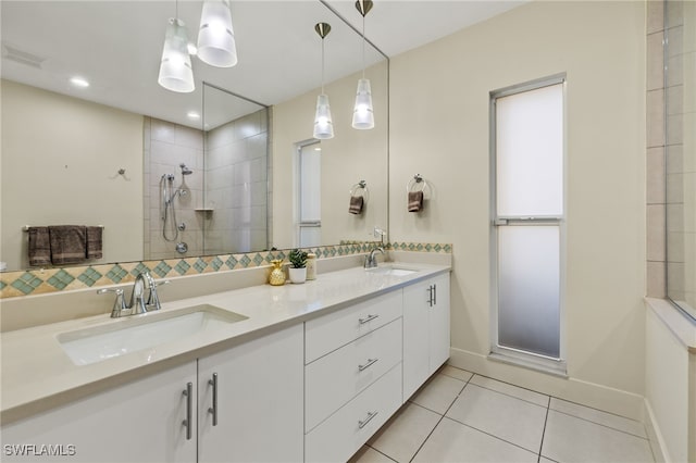 bathroom featuring tile patterned flooring, a tile shower, and vanity