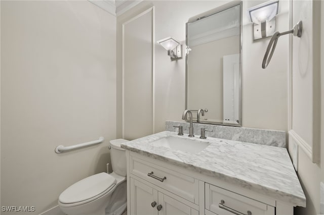 bathroom featuring toilet, vanity, and ornamental molding