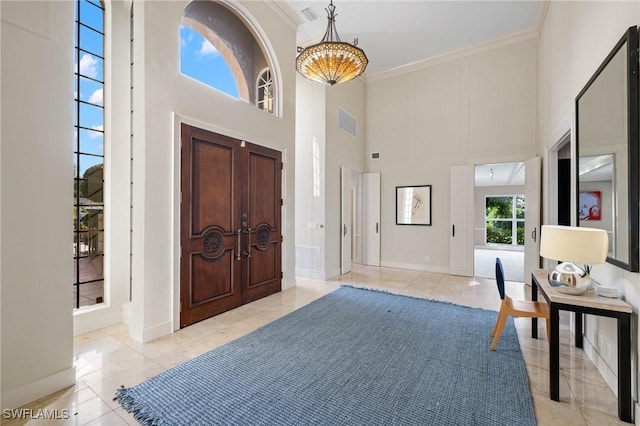 tiled foyer entrance with a high ceiling and ornamental molding