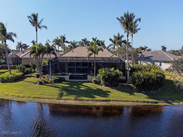 back of house featuring glass enclosure, a yard, and a water view