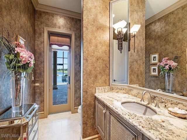 bathroom with toilet, vanity, crown molding, and tile patterned flooring