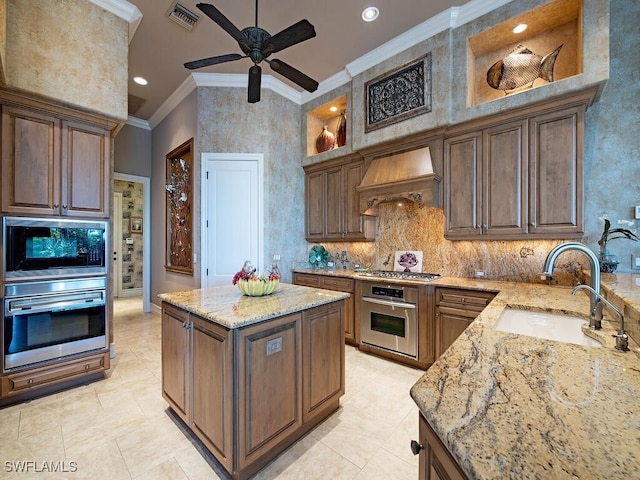 kitchen featuring custom exhaust hood, appliances with stainless steel finishes, crown molding, light stone counters, and sink