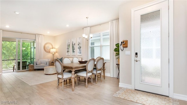 dining area with a wealth of natural light, a chandelier, and light hardwood / wood-style flooring