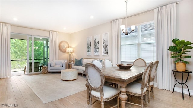 dining space featuring light wood-type flooring and an inviting chandelier