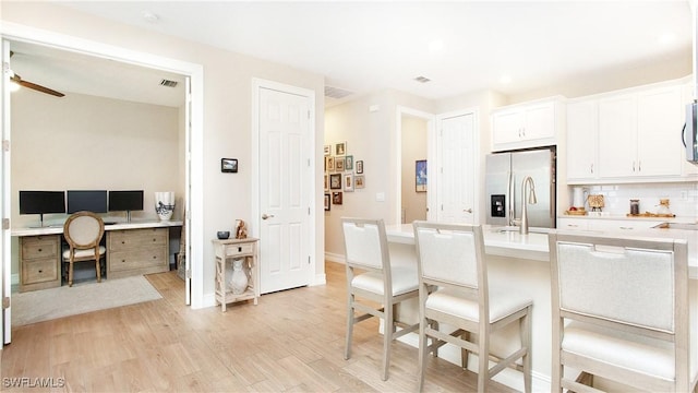 kitchen with light hardwood / wood-style floors, ceiling fan, appliances with stainless steel finishes, backsplash, and white cabinets