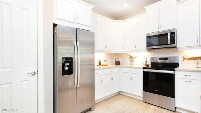 kitchen featuring appliances with stainless steel finishes, light hardwood / wood-style floors, white cabinetry, and tasteful backsplash