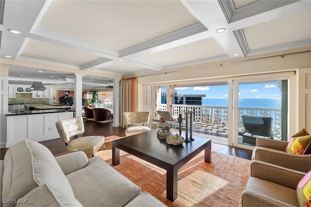 living room featuring beam ceiling, coffered ceiling, light hardwood / wood-style flooring, and a water view