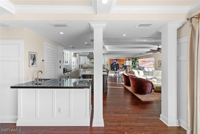 kitchen featuring sink, beamed ceiling, a kitchen bar, kitchen peninsula, and dark wood-type flooring