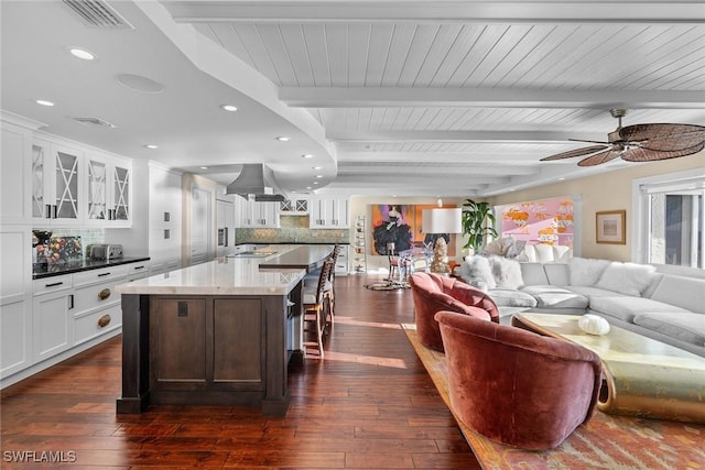 living room featuring ceiling fan, dark hardwood / wood-style floors, and beamed ceiling