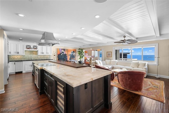 kitchen featuring beverage cooler, island exhaust hood, a water view, beamed ceiling, and ceiling fan