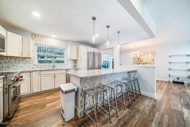 kitchen with decorative light fixtures, hardwood / wood-style flooring, a breakfast bar area, white cabinets, and high quality appliances