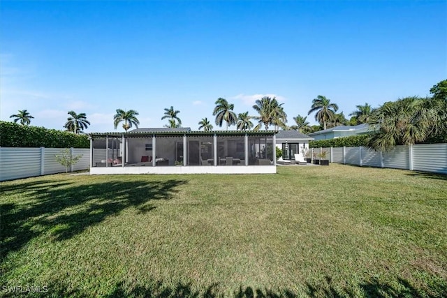 rear view of house featuring a yard and a sunroom