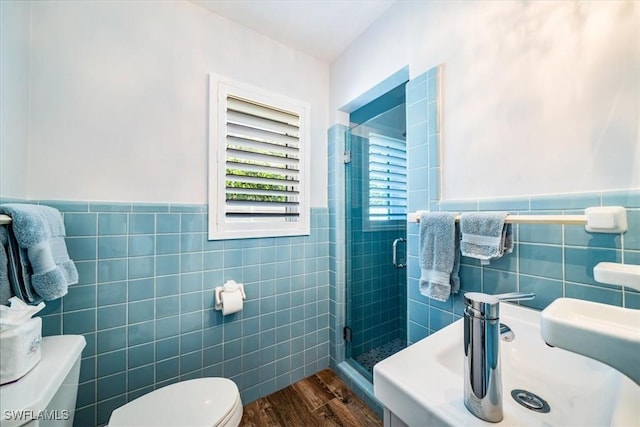 bathroom with walk in shower, toilet, tile walls, wood-type flooring, and sink