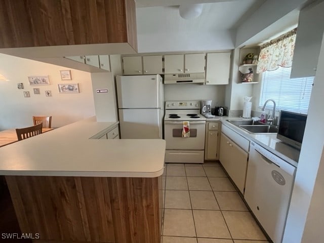 kitchen featuring kitchen peninsula, light tile patterned flooring, white appliances, and sink