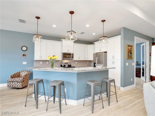 kitchen featuring white cabinets, backsplash, light stone counters, and appliances with stainless steel finishes